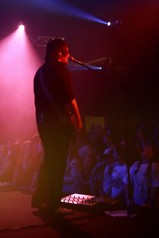 a male with a microphone and a concert on stage