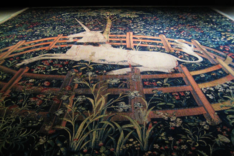 an ornate tapestry with a unicorn laying on a fence