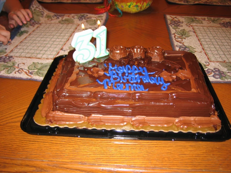 a birthday cake that has chocolate frosting and lit candles