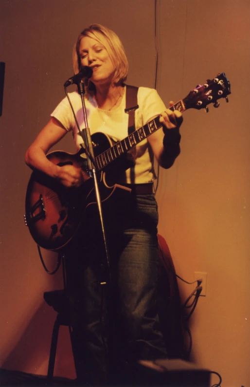 a woman playing the guitar while performing on stage