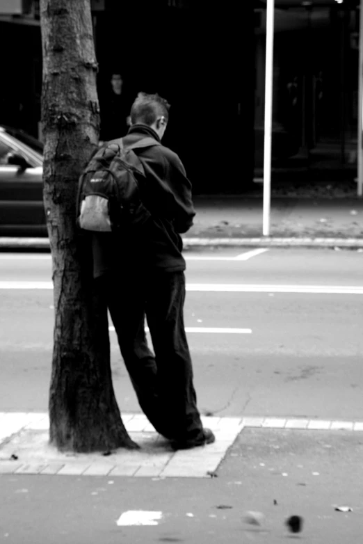 a man leaning on a tree on the street