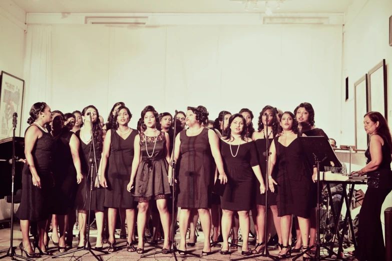 six women in dresses are performing with microphones