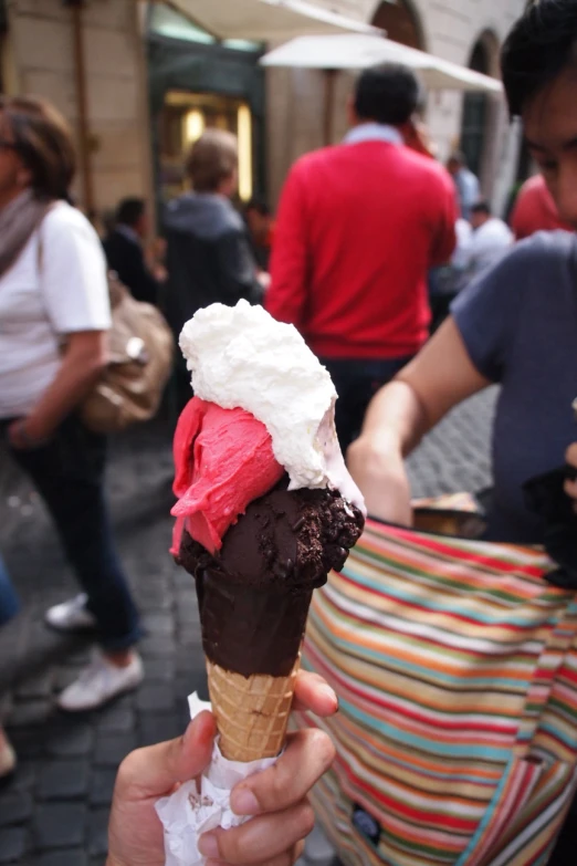 a person is holding an ice cream cone on a street