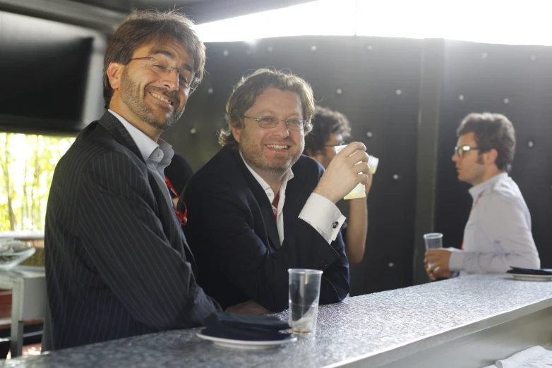 two men standing near each other at the bar