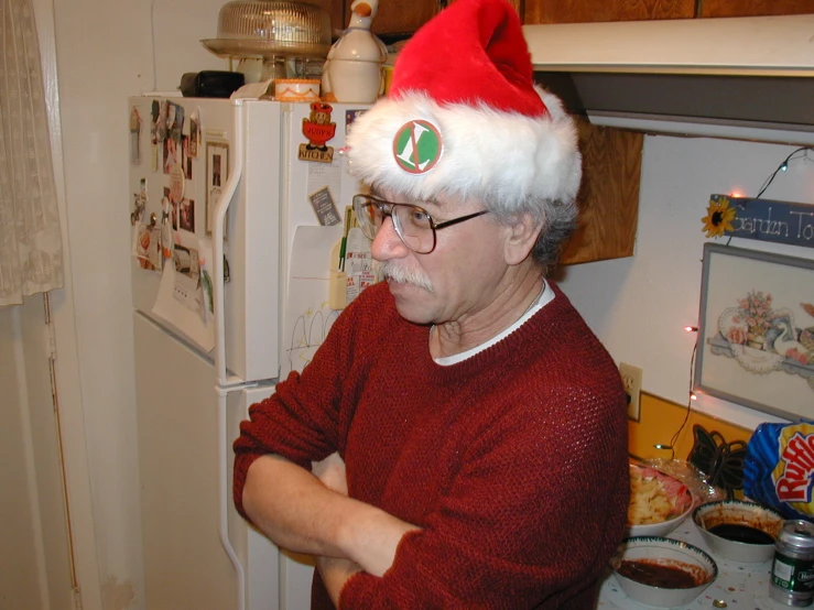 a man wearing a christmas hat while standing in front of a refrigerator