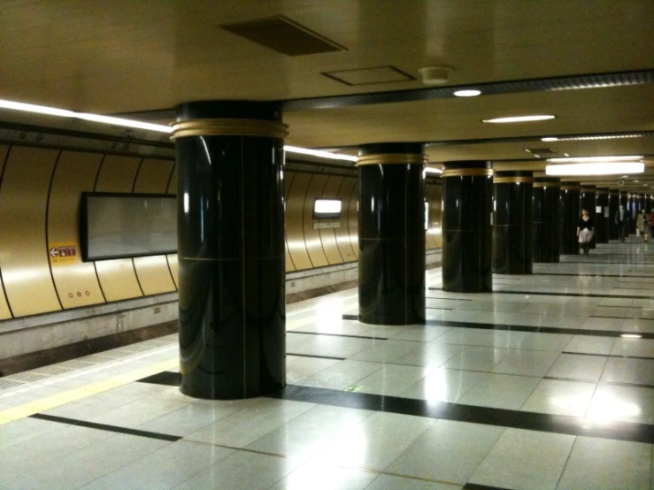 a public transportation subway with black pillars and gold tiled floor