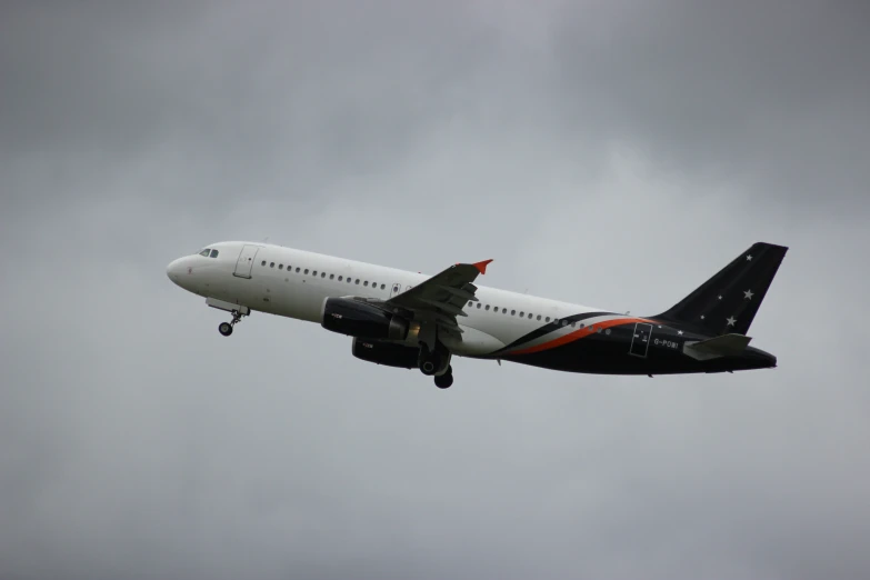 an airplane with a jetliner painted orange and white is flying in the sky