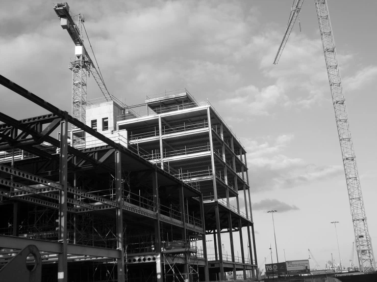 cranes are in front of a building under construction