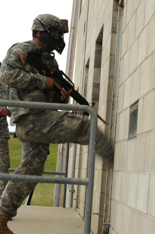 soldier in camouflage with rifle and gun walking up stairs to building