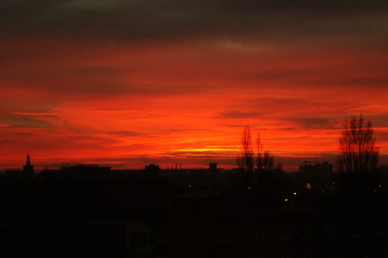 the sky is red as the sun sets behind the building