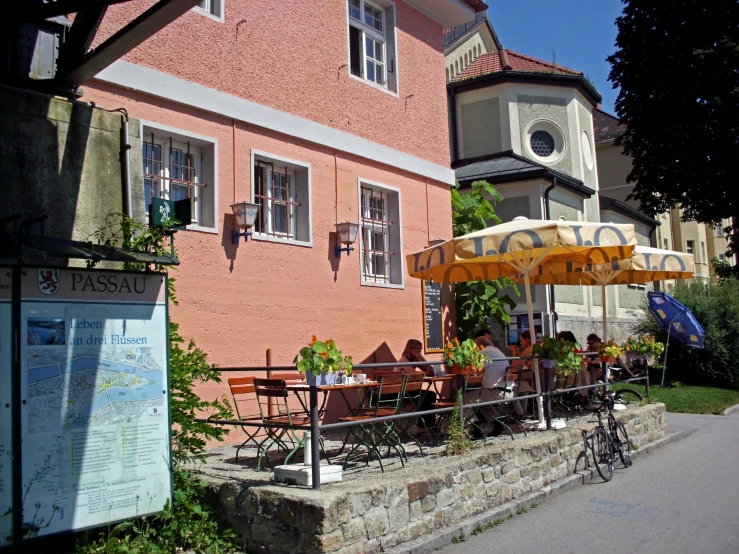 a couple of buildings with tables and chairs under an umbrella