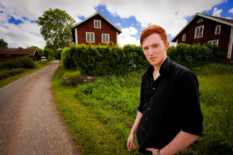 the man is standing outside in the grass near some houses