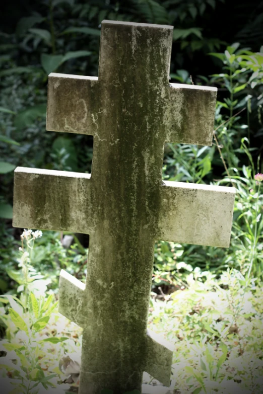 a cross placed in some grass and bushes