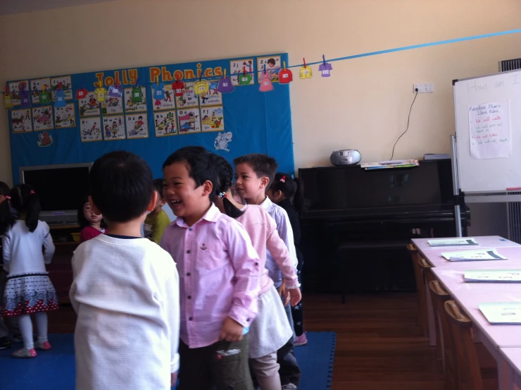children wearing pink are in a classroom with blue rugs
