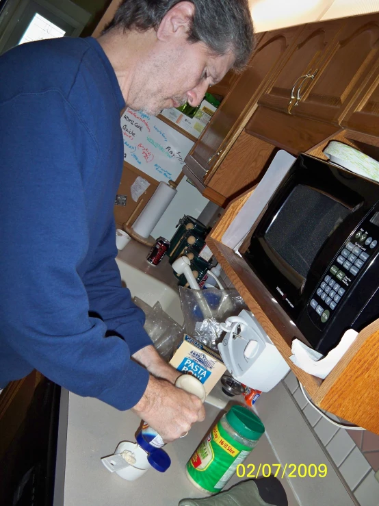 a man in the kitchen putting a liquid into the mixer