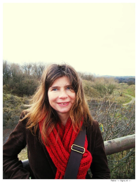 a young woman standing in front of a wood fence