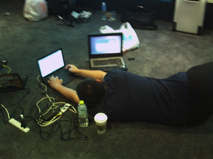 a man laying on the floor working on his laptop