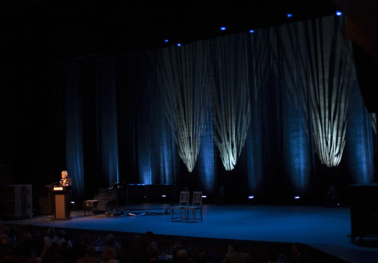 the man is standing on the stage giving a talk