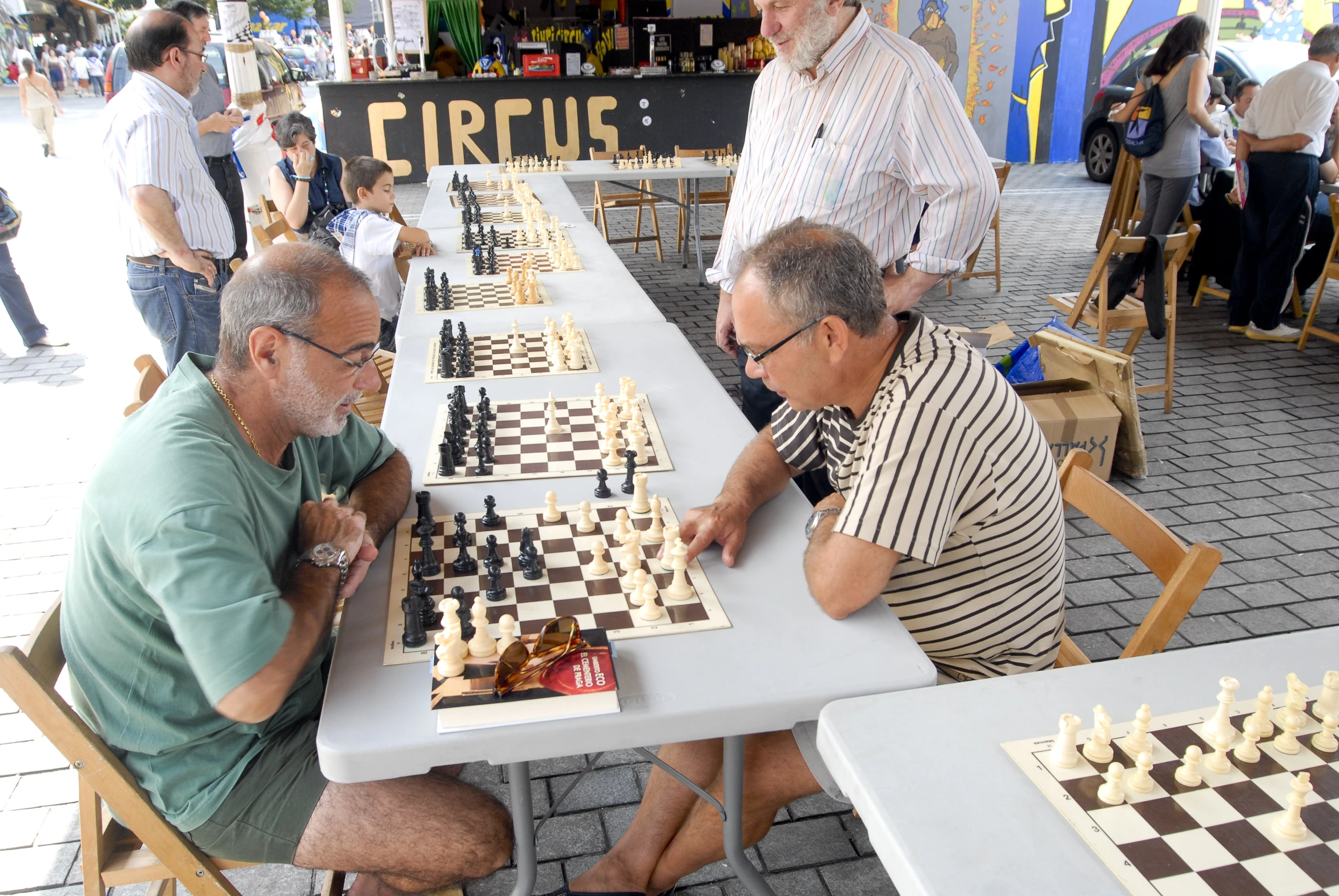 some guys are sitting at a table with chess