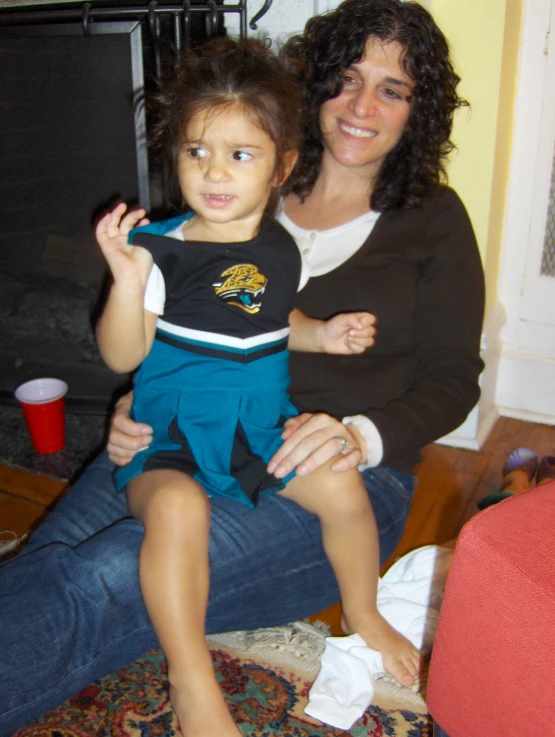 a little girl sitting on top of her mother's lap