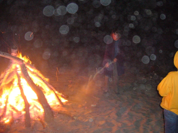 two people standing next to an open campfire