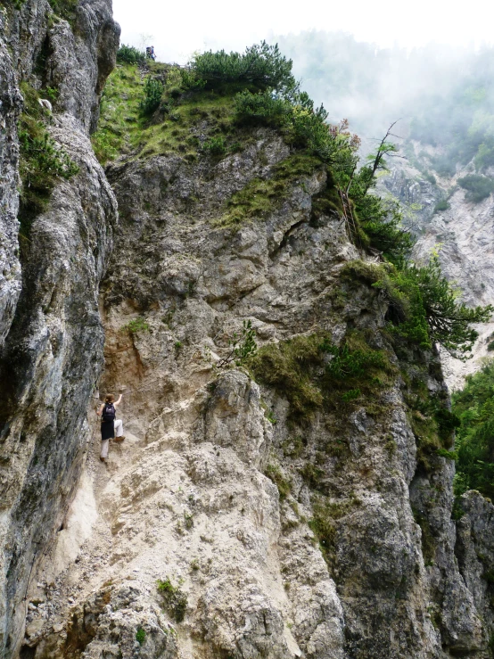 a cave like area with grass and rocks on a cliff face