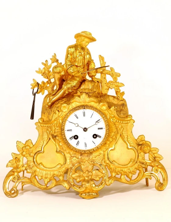 an elaborate clock with decorative gold pieces against a white background