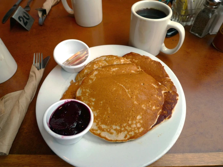 the white plate has pancakes on it next to some jam
