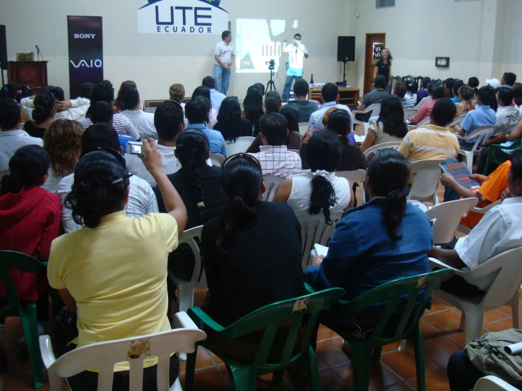 a man in a white shirt giving a presentation to a room full of people