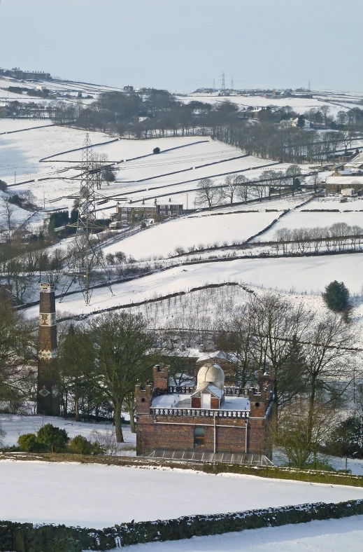 a snow covered field with a building on the edge and trees in the background