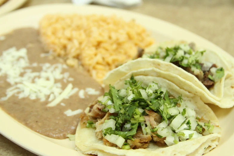 an image of three tacos and rice on a plate