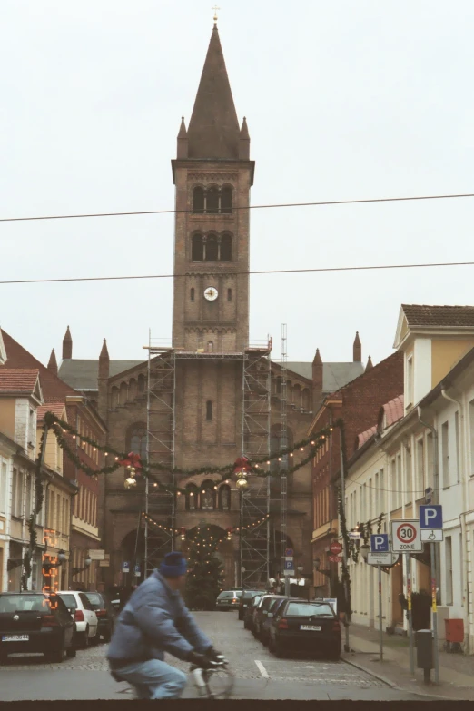 a cyclist going down a narrow city street in front of a church