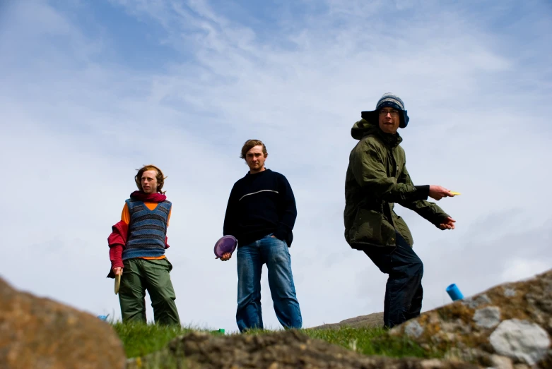 three people stand on a hill and watch soing