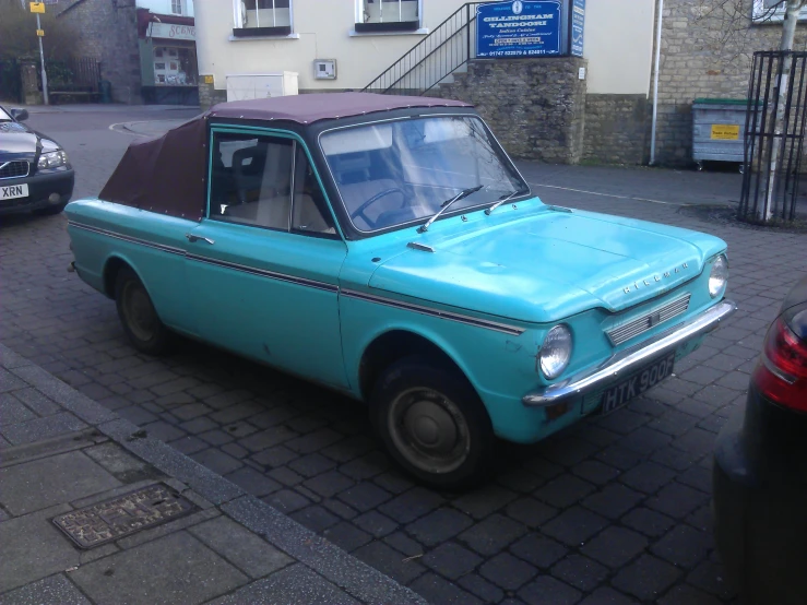 an older fashioned blue car is parked on the street