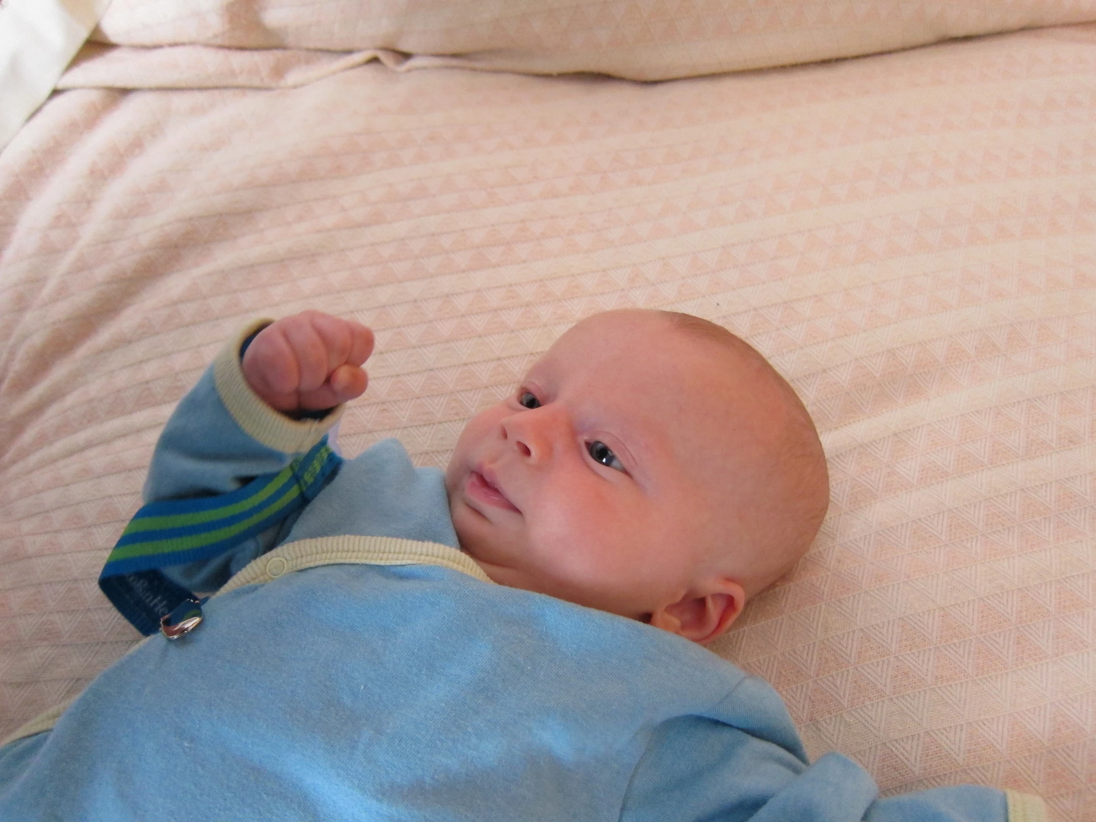 a baby laying on it's back and holding a thumb up