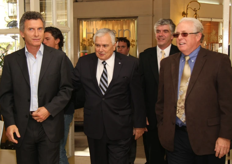 four men walk together in the lobby while others look on