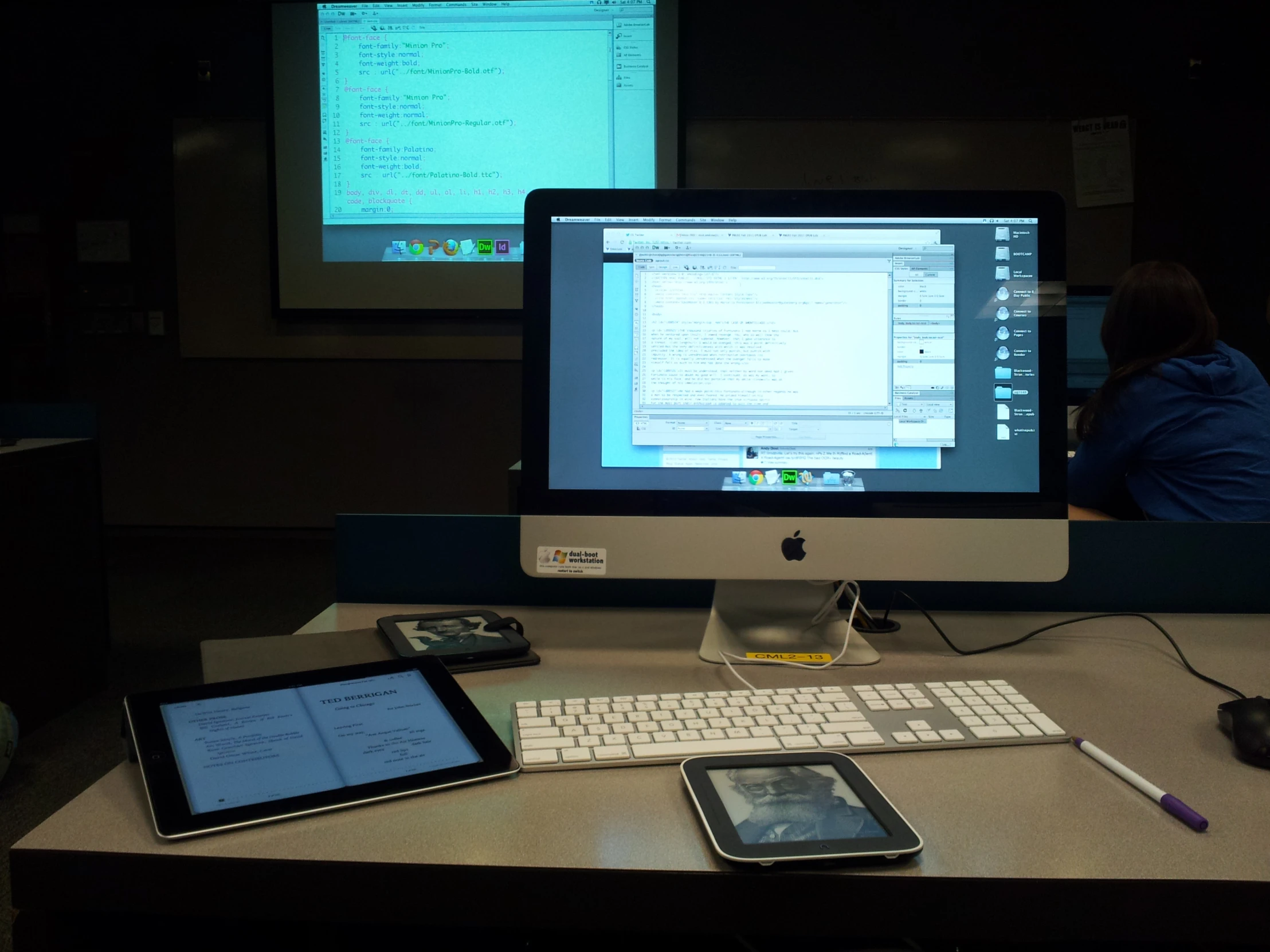 a computer desk with a keyboard, tablet, phone and a monitor