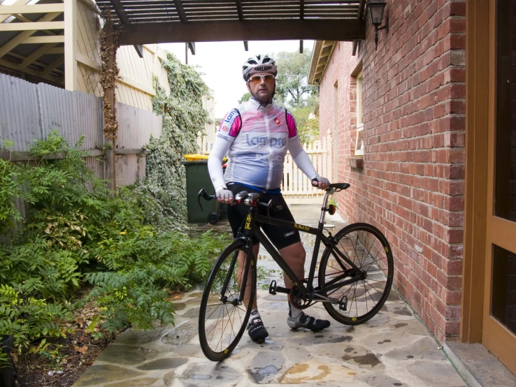 a man is standing with his bike under a pergolized structure