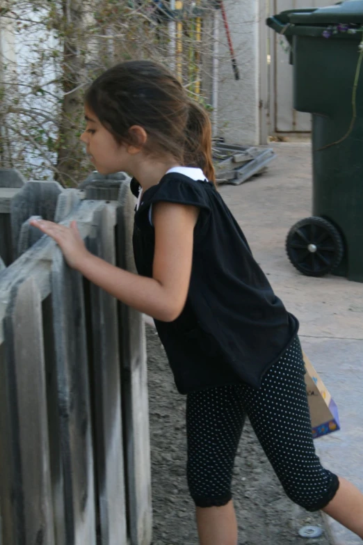 a  leaning against the wall reaching into a fence