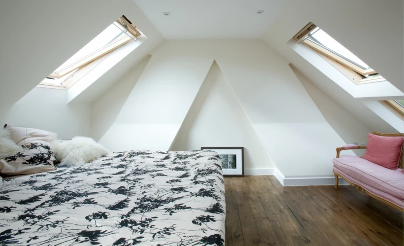 an unmade bed is under two skylights