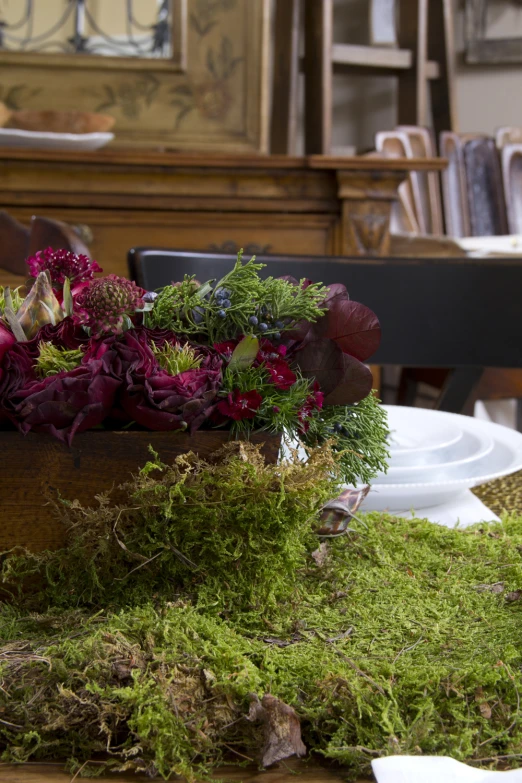 a box of flowers with green moss and a white plate