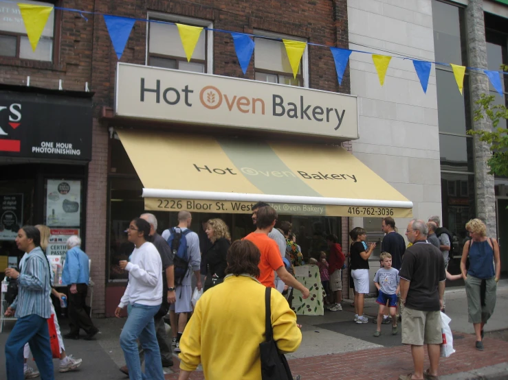 an image of people walking around outside of a bakery
