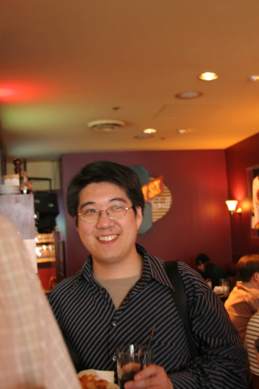 two men smile for a po while one holds a wine glass