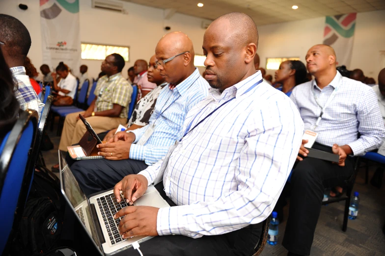 people seated at desk in a meeting with laptops