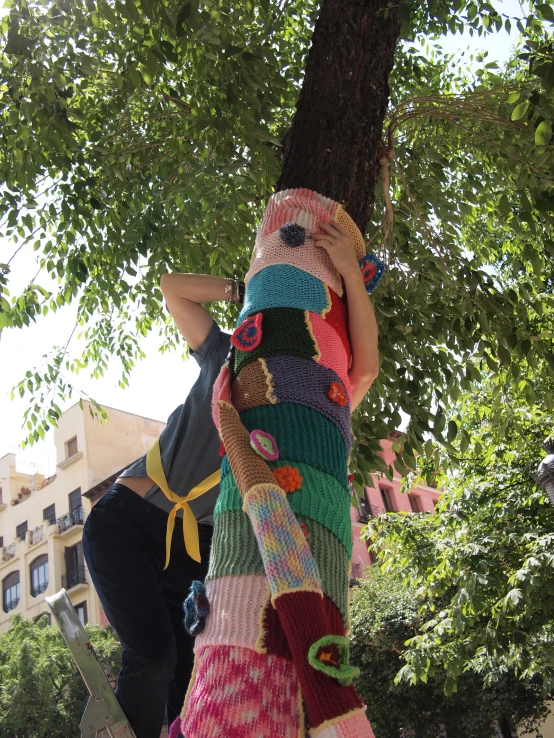 a person leaning on a tree and wearing a sweater