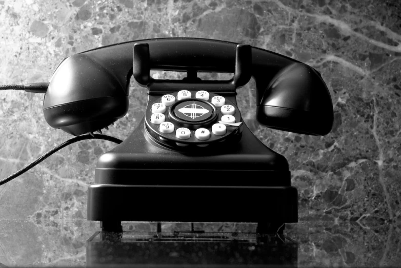 an antique black telephone with ons on a black stand