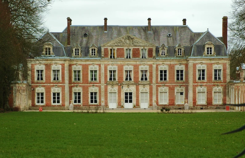 the front view of a building with green grass and trees