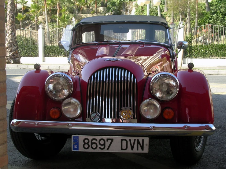 the front view of an antique red car parked in a driveway