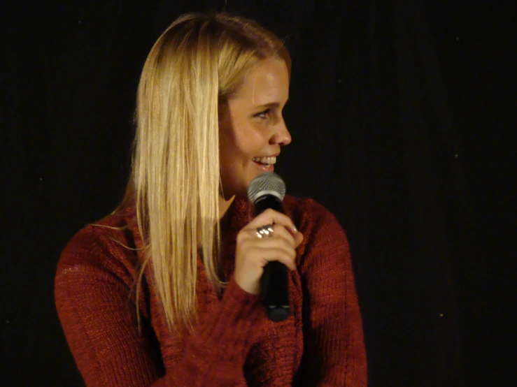 woman with long blonde hair speaking into a microphone