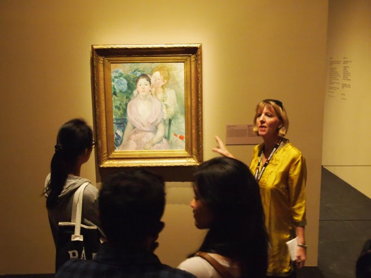 an old woman standing next to two ladies looking at a painting